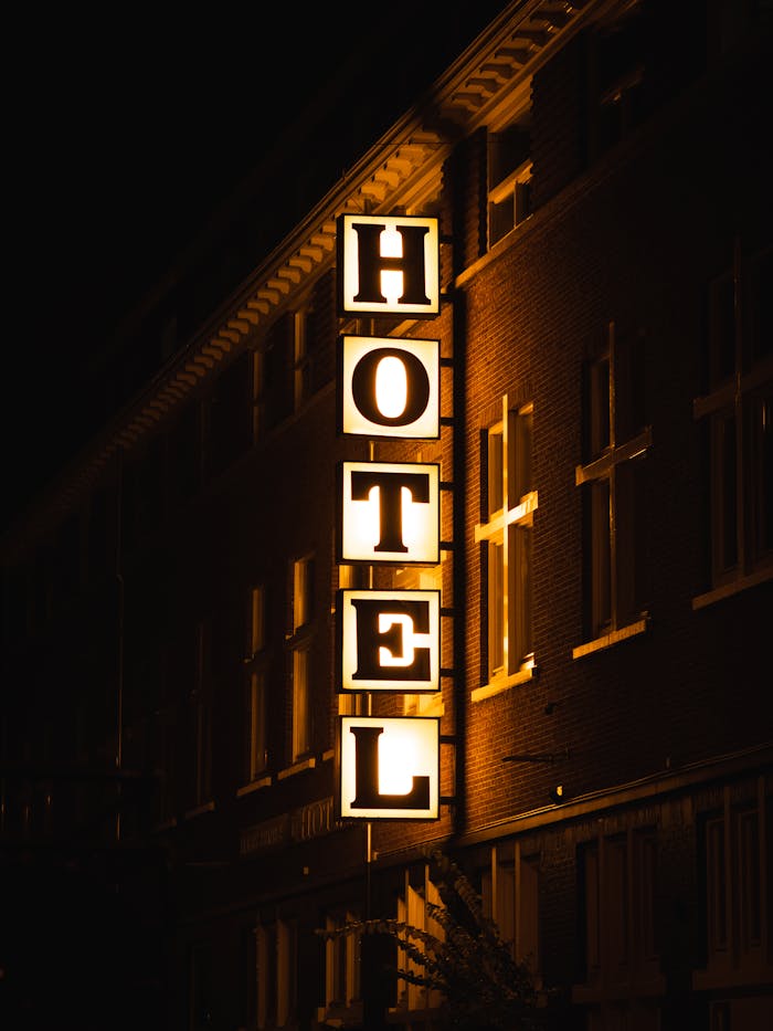who-we-are A bright hotel sign glowing on a building facade during nighttime.